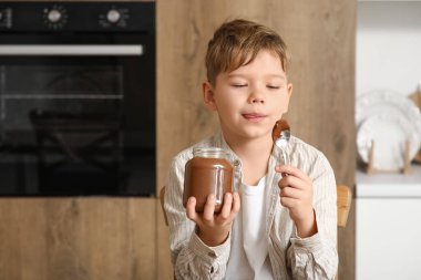 Mutfakta bir kavanoz çikolata ezmesi olan tatlı bir çocuk.