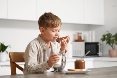Tatlı küçük çocuk tost yiyor. Çikolata ezmeli ve sütlü.