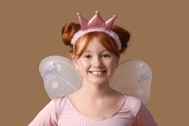 Kahverengi arka planda peri kostümlü tatlı kız.