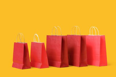 Sarı arka planda bir sürü kırmızı alışveriş torbası