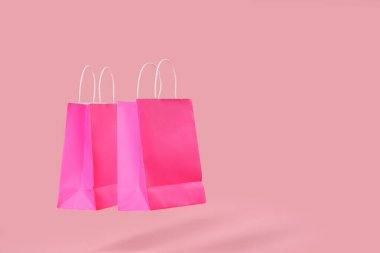 Renkli arkaplanda pembe alışveriş torbaları