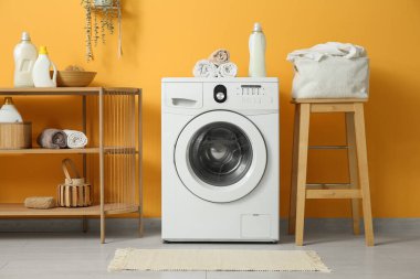 Modern çamaşır makinesi, raf ünitesi ve deterjan şişeleriyle şık bir çamaşır odası.