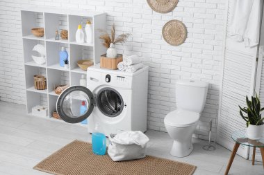 Modern çamaşır makinesi, raf ünitesi, klozet ve deterjan şişeleriyle şık bir çamaşır odası.