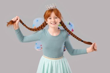 Gri arka planda örgüleri olan sevimli kızıl saçlı peri.