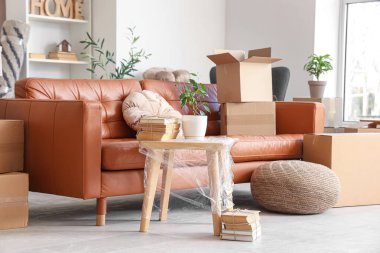 Taşındığı gün oturma odasında masa ve karton kutular olan kanepe