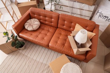 Hareket gününde oturma odasında karton kutular olan kahverengi kanepe, üst manzara.