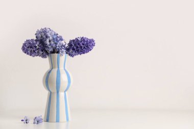Beyaz arka planda güzel mor sümbül çiçekleri olan vazo.