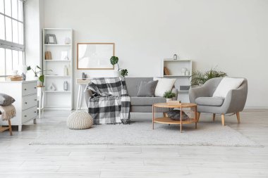 Gri kanepesi, koltuğu ve masası olan bir oturma odası.