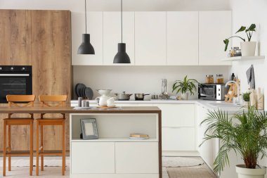 Tezgahları, masaları ve lambaları olan modern mutfağın içi.