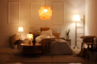 Şık yatak odasının bulanık manzarası rahat yatağı, çiçekleri ve geceleri parlayan lambaları.