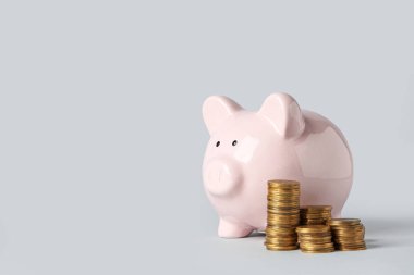 Gri arka planda bozuk paraları olan domuz kumbarası