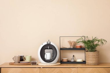 Modern kahve makinesi, fincanlar, ev bitkisi ve tezgahta bir kase fasulye.