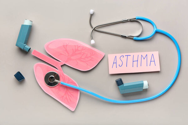 Ингаляторы, бумажные легкие, стетоскоп и бумажный лист с текстом ASTHMA на сером фоне