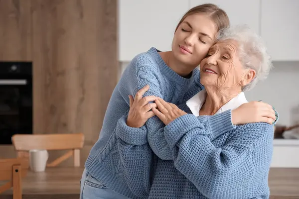 Mutlu son sınıf öğrencisi kadın ve torunu mutfakta sarılıyorlar.