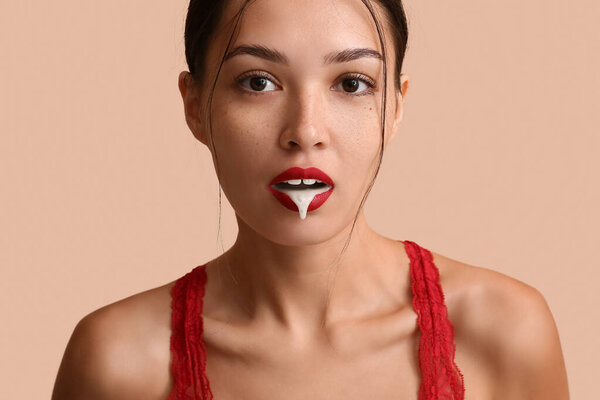 Сексуальная азиатка с белой жидкостью, капающей изо рта на цветном фоне, крупным планом. Эротическая концепция