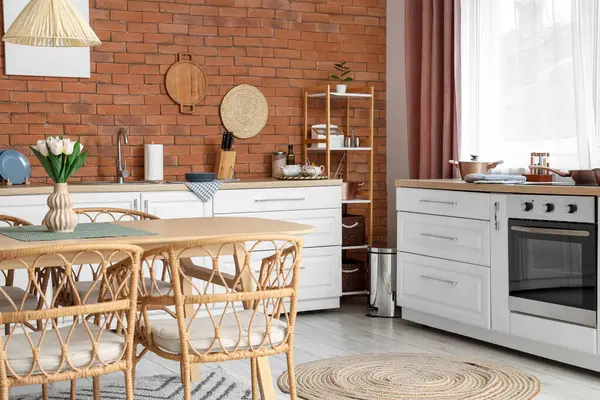 Tezgahları, raf ünitesi ve yemek masası olan modern mutfağın içi.