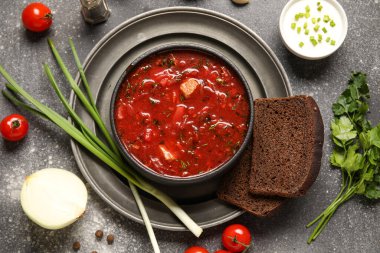 Ekmek dilimleri ve koyu arkaplanda malzemelerle bir kase lezzetli Ukrayna çorbası.