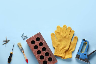 Mavi arka planda tuğla, eldiven ve inşaat araçları