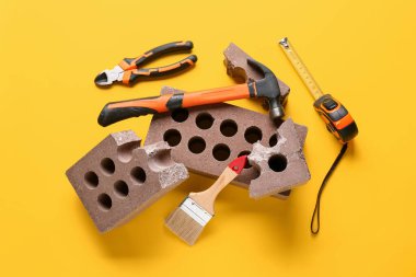 Sarı arkaplanda tuğla ve inşaat araçları