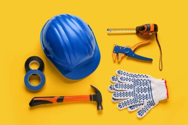 Sarı arkaplanda sert şapka ve inşaat araçları