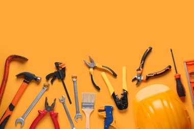 Turuncu arka planda sert şapka ve inşaat araçları