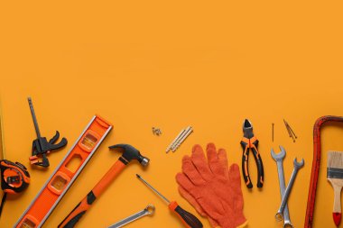 Turuncu arkaplanda eldivenler ve inşaat araçları