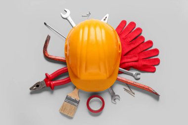 Gri arkaplanda sert şapka ve farklı inşaat araçları