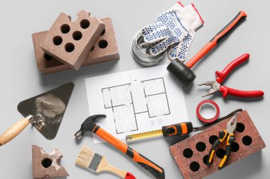 Gri arkaplanda ev planı, tuğla ve inşaat araçları