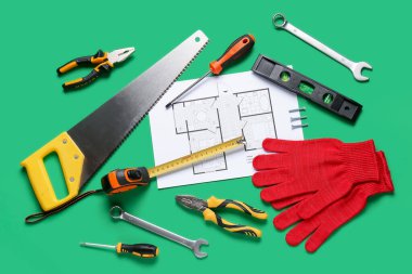 Yeşil arka planda ev planı ve inşaat araçları