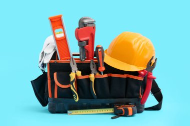 Mavi arkaplanda inşaat aletleri ve kasketli çanta