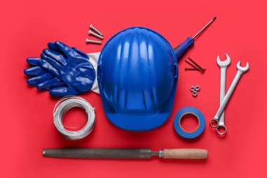 Kırmızı arkaplanda sert şapka ve inşaat araçları