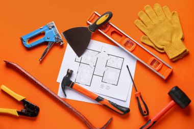 Turuncu arka planda ev planı ve inşaat araçları