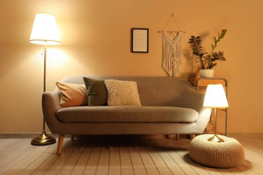 Gri kanepeli, puf ve parlayan lambalı şık bir oturma odası.