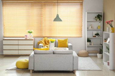 Anneler Günü için dekore edilmiş oturma odasının içinde kanepeler, masa ve raf üniteleri var.