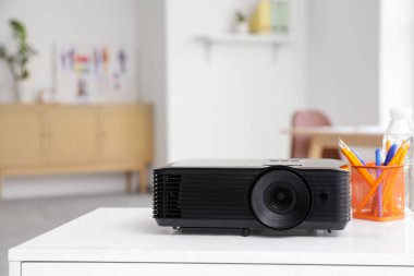 Ofisteki tasarımcının masasında kurşun kalem bardağı ve su şişesi olan modern projektör.