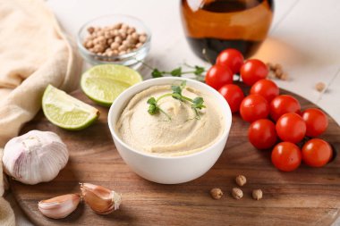 Tahta üzerinde malzemeler olan bir kase lezzetli humus, yakın plan.