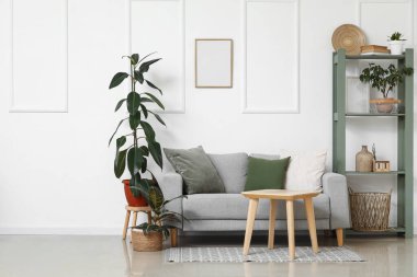 Gri kanepesi, sehpası ve raf ünitesi olan şık bir oturma odası.