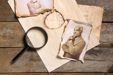 Ahşap arka planda, mektup ve büyüteçle akrabaların eski fotoğrafları. Aile ağacı kavramı