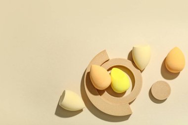 Sarı arka planda makyaj süngeri olan dekoratif podyumlar