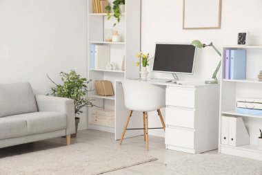 Çalışma odası, raf üniteleri ve kanepe.