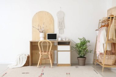 Ofisin içinde işyeri, vazoda çiçek açan dallar ve elbise askılığı.