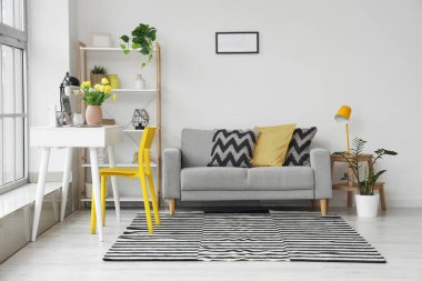 Ofisin içinde iş yeri, vazo ve kanepede bahar çiçekleri.