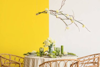 Narcissus çiçekleri, mumlar ve hafif yemek odasında sallanan ağaç dalları olan zarif bir masa.