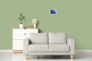 Oturma odasının içinde kanepe ve akıllı ev güvenlik kontrol paneli var.