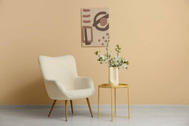 Beyaz koltuklu ve sehpanın üzerinde çiçek açan ağaç dalları olan şık bir oturma odası.