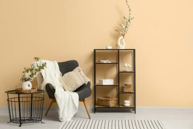 Gri koltuklu, raf üniteli ve sehpanın üzerinde çiçek açan ağaç dalları olan şık bir oturma odası.