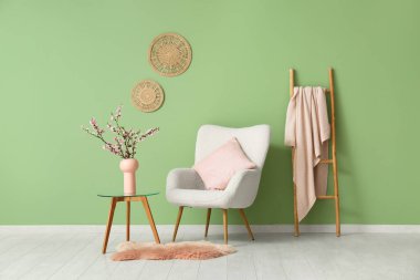 Beyaz koltuklu ve sehpanın üzerinde çiçek açan ağaç dalları olan şık bir oturma odası.