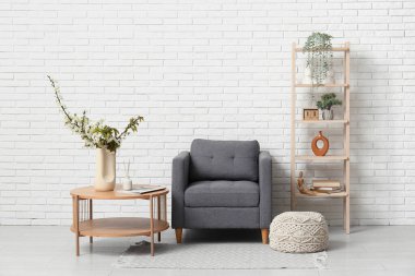 Gri koltuğu ve kahve masasının üzerinde çiçek açan ağaç dalları olan şık bir oturma odası.