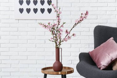 Modern gri koltuğu ve sehpanın üzerinde çiçek açan ağaç dalları olan şık bir oturma odası.