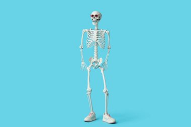 Güneş gözlüklü komik insan iskeleti ve mavi arka planda spor ayakkabıları.